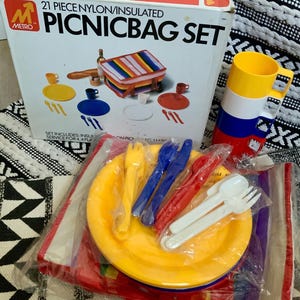 May include: A 21-piece picnic set with a nylon insulated bag, plates, cups, forks, knives, and spoons. The set is packaged in a box with a red, white, and blue color scheme.