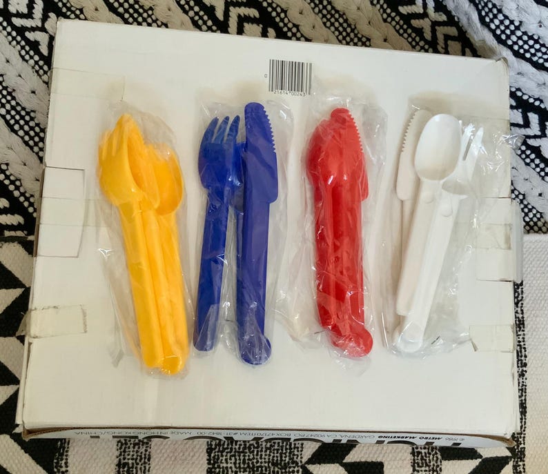 May include: A set of six plastic utensils in individual packaging. The utensils are yellow, blue, red, and white. The utensils include a fork, knife, and spoon.