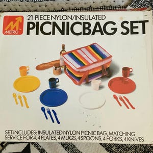 May include: A 21-piece picnic set with a rainbow insulated nylon bag, four plates, four mugs, four spoons, four forks, and four knives. The set is packaged in a white box with the Metro logo and the text "21 Piece Nylon/Insulated Picnic Bag Set".