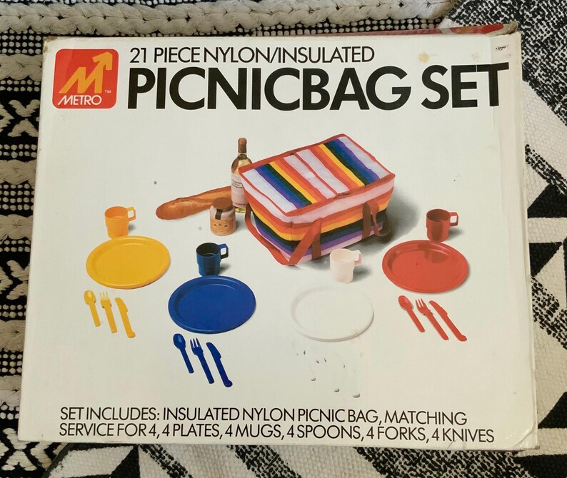 May include: A 21-piece picnic set with a rainbow insulated nylon bag, four plates, four mugs, four spoons, four forks, and four knives. The set is packaged in a white box with the Metro logo and the text "21 Piece Nylon/Insulated Picnic Bag Set".
