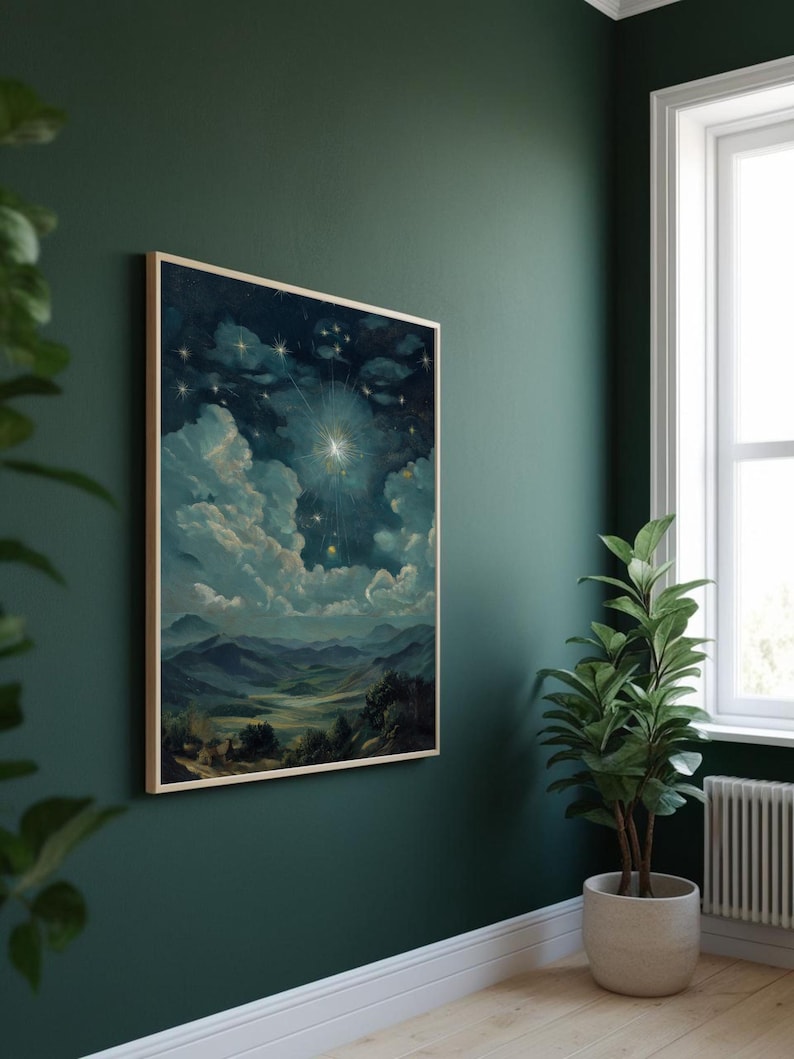 Puede incluir: Una pintura de paisaje enmarcada representa una escena celestial con una brillante explosi&oacute;n de estrellas, nubes y monta&ntilde;as. La obra de arte, en tonos de azul, verde y blanco, se exhibe en una pared verde oscuro. Una planta en maceta se encuentra cerca, agregando un toque de naturaleza a la habitaci&oacute;n.