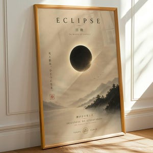 Op de afbeelding: Ingelijste kunstdruk met het woord "ECLIPSE" bovenaan, met een afbeelding van een zonsverduistering. De afbeelding bevat Japanse tekst en een landschap van bergen en water. De lijst is lichtbruin.