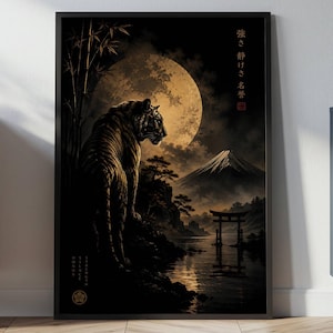 Op de afbeelding: Ingelijste kunstdruk met een tijger in een Japanse landschap. Het kunstwerk toont een tijger, een berg, een grote maan en een traditionele torii-poort. Het kleurenpalet omvat tinten zwart, goud en bruin.