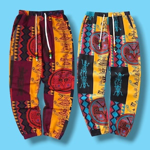 May include: Two pairs of patterned trousers with drawstring waists. One pair features a patchwork design in burgundy, yellow, and red with geometric and tribal motifs. The other pair has a similar style, with black, yellow, and turquoise patterns.