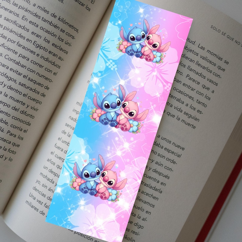 May include: A colorful bookmark featuring the characters Stitch and Angel from Lilo & Stitch. The design has a blue and pink gradient background with floral accents. The bookmark is rectangular and is placed on top of an open book.