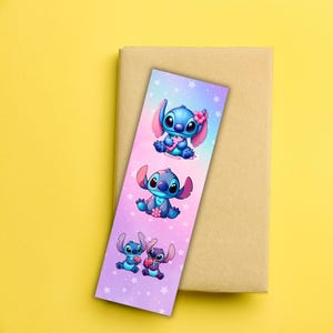 May include: A colorful bookmark featuring three illustrations of the character Stitch from the Disney movie Lilo & Stitch. The bookmark has a gradient background of pink, purple, and blue with white stars. Stitch is blue with pink ears and is holding a flower.