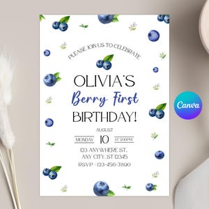May include: White invitation featuring watercolour blueberries and green leaves. Text reads "Please join us to celebrate Olivia's Berry First Birthday!" with date, time, and address details. Canva logo.