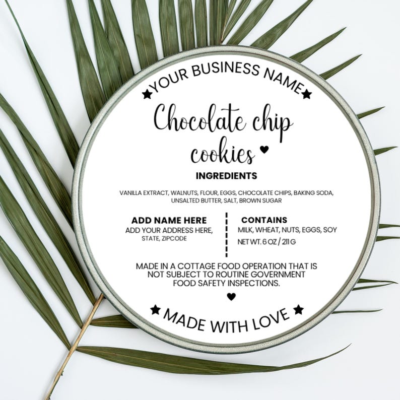 May include: A round tin with a label that reads "Chocolate chip cookies." The label lists ingredients and allergen information. The tin is surrounded by green palm leaves. The net weight is 6 oz / 211 g.