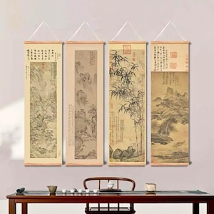 Könnte beinhalten: Vier vertikale Wandmalereien im asiatischen Stil mit Holzstäben und Aufhängeschnüren. Das Kunstwerk zeigt Landschaftsszenen mit Bergen, Bäumen und Kalligraphie in Beige-, Braun- und Schwarztönen. Die Schriftrollen werden an einer weißen Wand ausgestellt.