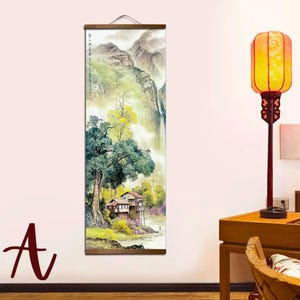 May include: A vertical landscape painting depicting a serene mountain scene with a waterfall, trees, and a small house. The artwork is mounted on a wooden scroll with a hanging cord. The color palette includes greens, browns, and whites.