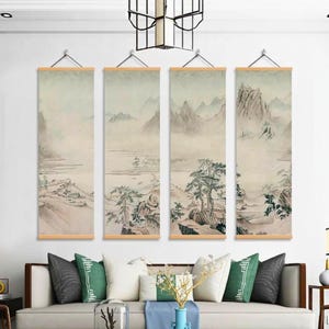 Könnte beinhalten: Vier vertikale Landschaftskunst-Drucke mit asiatischer Ästhetik. Jeder Druck zeigt eine neblige Berglandschaft in gedämpften Beige-, Grau- und Grüntönen. Die Drucke werden mit Holzstäben und Metallhaken aufgehängt, über einem Sofa mit dekorativen Kissen.