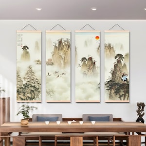 May include: Four vertical wall art panels depicting a traditional Chinese landscape. Each panel features mountains, trees, and misty clouds, with some including birds and a red sun. The art is framed with wooden rods and hung on a white wall.