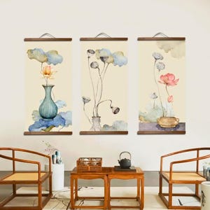 Könnte beinhalten: Set aus drei vertikalen Wandkunstwerken mit Aquarellmalereien von Blumen in Vasen. Jedes Stück hat einen Holzrahmen und einen Metallaufhänger. Die Kunstwerke zeigen eine Vielzahl von Farben, darunter Blau, Rosa und Gelb.