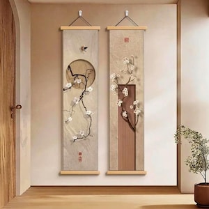 Peut inclure: Deux œuvres d'art murales verticales avec un fond beige, représentant des branches florales et un motif circulaire. L'art a des chevilles en bois en haut et en bas pour l'accrochage. L'œuvre est de style minimaliste.