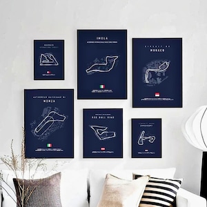 May include: A collection of framed racing circuit maps, each with a dark blue background and white line art. The maps include circuits like Imola, Monaco, and Monza, with flags at the bottom. The frames are black.