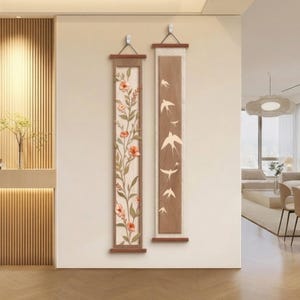 Pode incluir: Dois painéis verticais de parede com molduras de madeira. A peça da esquerda apresenta um fundo claro com um design floral em relevo de flores laranja e folhas verdes. A peça da direita exibe um painel central castanho com aves brancas.