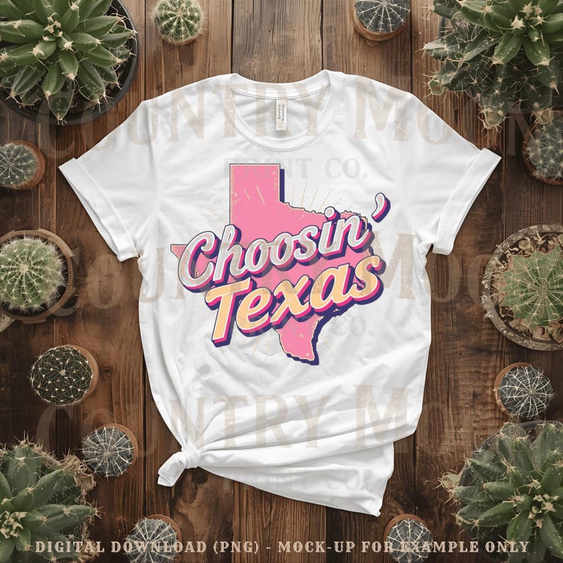 May include: White t-shirt with a pink outline of Texas and the text "Choosin Texas" in a retro font. The design uses pink, yellow, and purple. The shirt is displayed on a wooden surface, surrounded by cacti in pots.