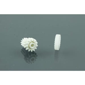 May include: Two white plastic gears are displayed against a gray background. One gear is positioned on its side, showcasing its toothed edge, while the other is upright, revealing its central hole and intricate design. The gears appear to be new.