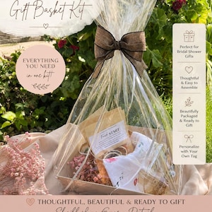 May include: A bridal shower gift basket kit wrapped in a clear cellophane bag with a brown ribbon bow. The kit includes a gift box, crinkle paper, a glass simmer pot, three simmer kits, a tea towel, and a gift tag, all displayed in a clear package.