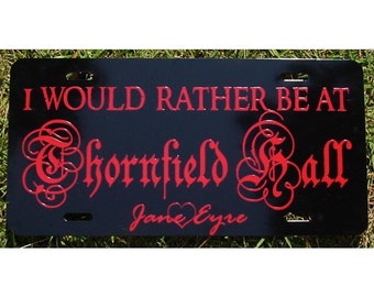 May include: Black metal license plate with red text that reads "I would rather be at Thornfield Hall Jane Eyre".