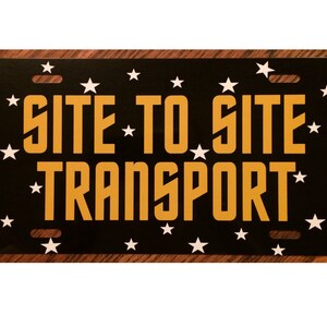 May include: Black metal license plate with white stars and the text "SITE TO SITE TRANSPORT" in yellow letters.
