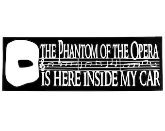 May include: Black and white bumper sticker with a white phantom of the opera mask and the text "The Phantom of the Opera is here inside my car".