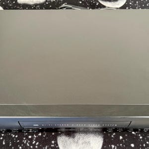 Op de afbeelding: Een zwarte RCA videorecorder met een rechthoekige behuizing en een cassettegleuf aan de voorzijde. Het voorpaneel bevat de tekst RCA en Hi-Fi Stereo 4 Head Video System, samen met diverse bedieningsknoppen voor afspeel- en opnamefuncties.