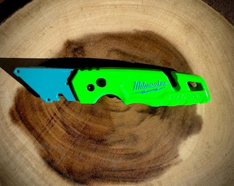 May include: A green and blue utility knife with a black handle and the word "Milwaukee" printed on the side.