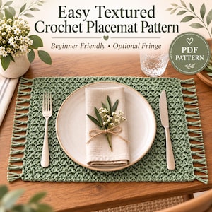 May include: A sage green rectangular crochet placemat with fringe on the short sides. The text reads: Easy Textured Crochet Placemat Pattern, Beginner Friendly, Optional Fringe, PDF PATTERN. A white plate, napkin, fork, and knife are placed on top.