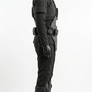 May include: A black tactical costume displayed on a mannequin, featuring a high-neck long-sleeve top with ribbed detailing, matching trousers, a utility belt with pouches, a shoulder strap with cylindrical attachments, and tall buckled boots.