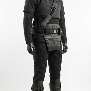 May include: A black tactical costume set on a mannequin, featuring a high-neck long-sleeve shirt, structured chest armor, a utility belt with a front panel, and matching trousers. The outfit includes tall black boots with straps and leg guards.