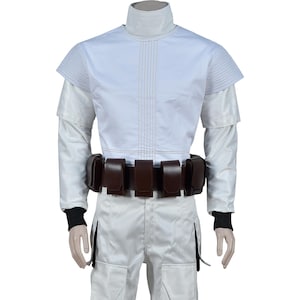 May include: White costume with a brown belt and multiple pouches. The costume has long sleeves and a high collar.