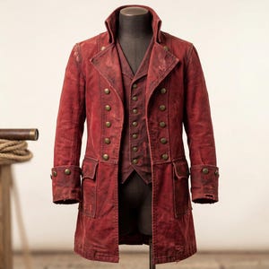Op de afbeelding: Een rode, dubbelzijdige jas en vest set met messing knopen. De jas heeft een hoge kraag, twee voorzakken en manchetten met knopen. Het vest is zichtbaar onder de jas. De outfit wordt op een mannequin gepresenteerd.