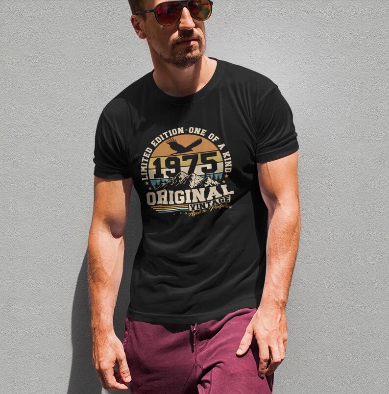 Puede incluir: Camiseta negra con un dise&ntilde;o gr&aacute;fico circular que presenta el a&ntilde;o "1975", monta&ntilde;as y un &aacute;guila. El dise&ntilde;o incluye las palabras "Edici&oacute;n Limitada - &Uacute;nica" y "Original Vintage".
