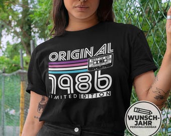 May include: Black t-shirt with the text "ORIGINAL 1986 LIMITED EDITION" in white. The design includes a retro cassette tape graphic and a color block of purple, pink, and blue stripes. The shirt is a short-sleeved crew neck.