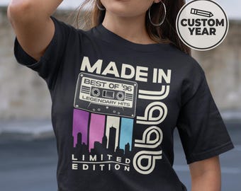 May include: Black t-shirt with a retro design. The shirt features the text "MADE IN '96" with a cassette tape graphic and the words "BEST OF '96" and "LEGENDARY HITS". Below the tape is a skyline graphic and the words "LIMITED EDITION".