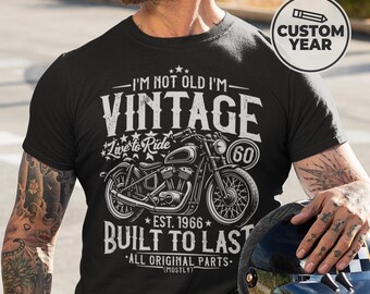 May include: Black t-shirt with a vintage motorcycle graphic and the text "I'M NOT OLD I'M VINTAGE". The shirt also features the text "Live to Ride", "Built to Last", and "EST. 1966". A custom year can be added.