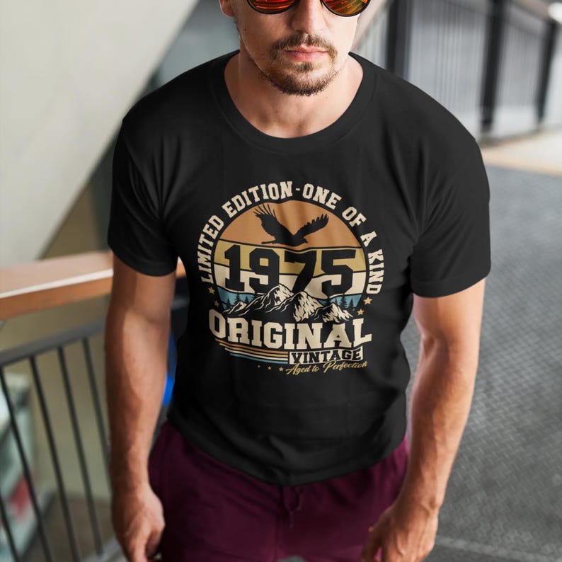 Puede incluir: Camiseta negra con un dise&ntilde;o vintage que presenta el a&ntilde;o "1975", monta&ntilde;as y un &aacute;guila. La camiseta tiene el texto "Limited Edition - One of a Kind" y "Original Vintage Aged to Perfection".