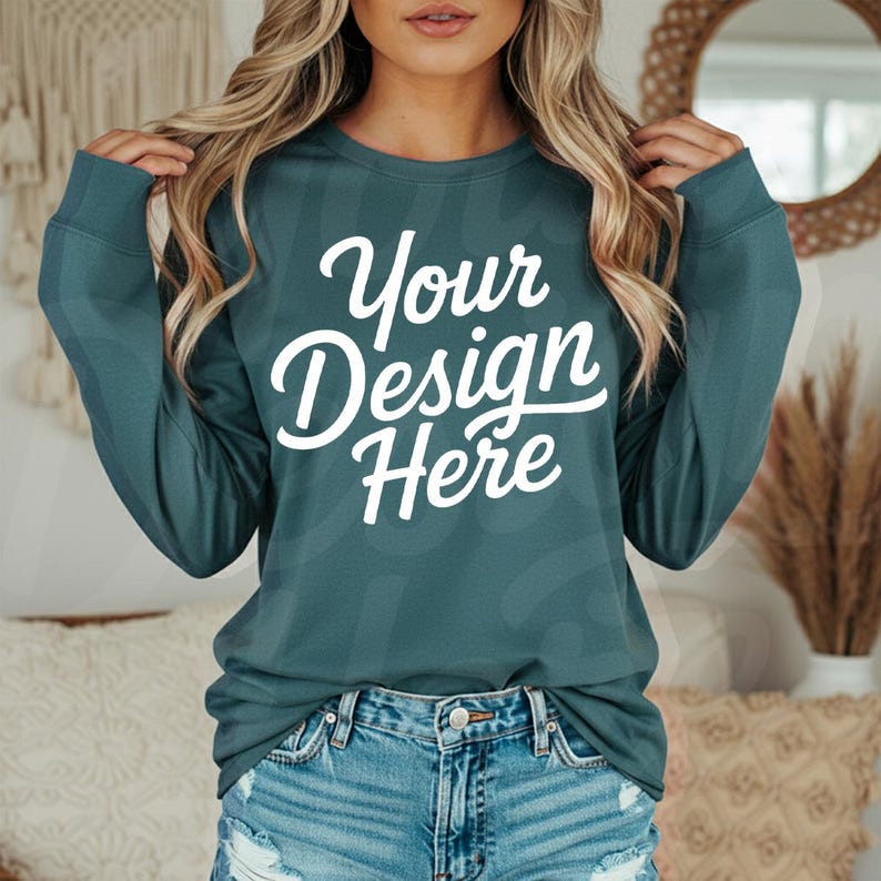 May include: Teal long-sleeve shirt with the text "Your Design Here" in white script. The shirt is paired with denim shorts. The image is a mockup, likely for showcasing custom designs on apparel.