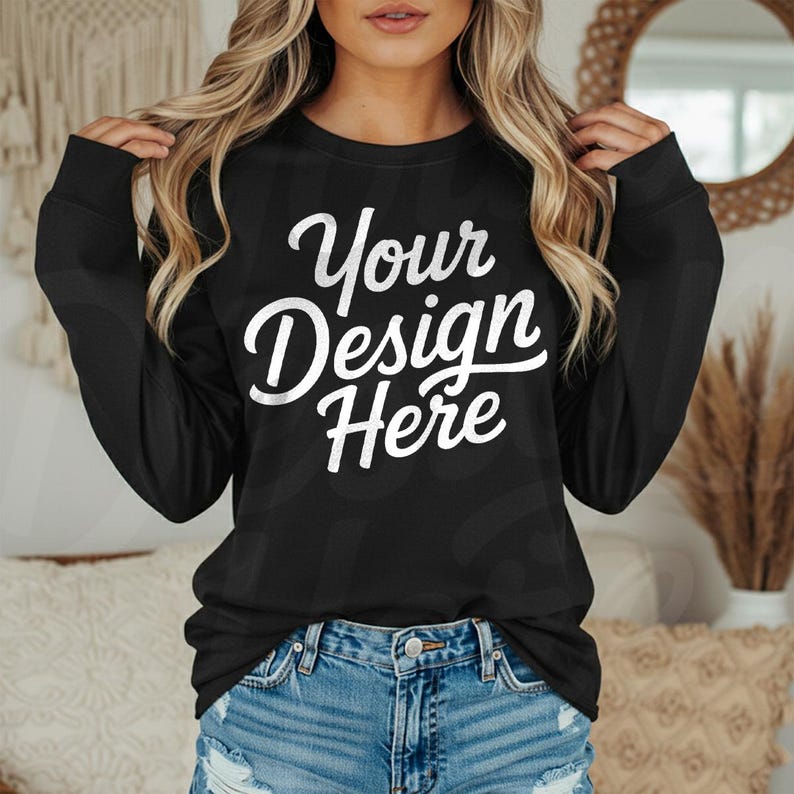 May include: Black long-sleeve sweatshirt with the text "Your Design Here" in white script. The sweatshirt is paired with blue denim shorts. The image is a product mockup, perfect for showcasing custom designs.