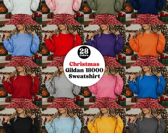 May include: A selection of women modelling Gildan 18000 sweatshirts in a variety of colours, such as white, pink, green, and blue. The sweatshirts are worn with Christmas-themed pyjama bottoms. The image features a circular graphic with the text "28 Colors" and "Christmas Gildan 18000 Sweatshirt."