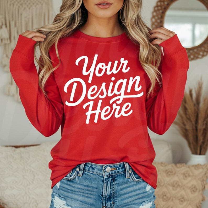 May include: A long-sleeved red sweatshirt with the text "Your Design Here" in white script. The sweatshirt is paired with blue denim shorts. The image is a product mockup, likely for apparel design.