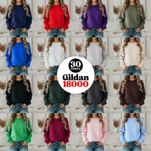 May include: A grid of crewneck sweatshirts in various colors, including navy, red, purple, and green. The image displays 30 different color options from the brand Gildan 18000. Each sweatshirt is shown on a person wearing blue jeans.