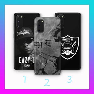 Puede incluir: Tres fundas negras para teléfono con diferentes diseños. Una funda presenta una imagen en blanco y negro de Eazy-E con un sombrero de Compton. Otra funda tiene un diseño gris y negro con el texto "Eazy E". La tercera funda muestra un diseño temático de los Raiders con la imagen de Eazy-E.