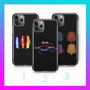 Könnte beinhalten: Drei schwarze Smartphone-Hüllen mit Teenage Mutant Ninja Turtles-Motiven. Hülle 1 zeigt drei farbige Waffensymbole. Hülle 2 zeigt vier farbige Augenmasken. Hülle 3 zeigt vier kreisförmige Embleme mit dem Text Mutant Proud.