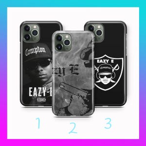 May include: Three black phone cases with different designs. One case features a black and white image of a person wearing a Compton hat and sunglasses, with the text "EAZY-E". Another case has a gray and white design with the text "Eazy E". The third case has a shield design with the text "EAZY E Compton".