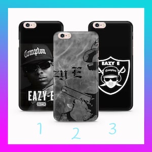 May include: Three black phone cases with different designs. One features a portrait of Eazy-E with the text "Compton" and "EAZY-E". Another has a smoky design with the text "Eazy E" and a gun. The third has a Raiders logo with Eazy-E.