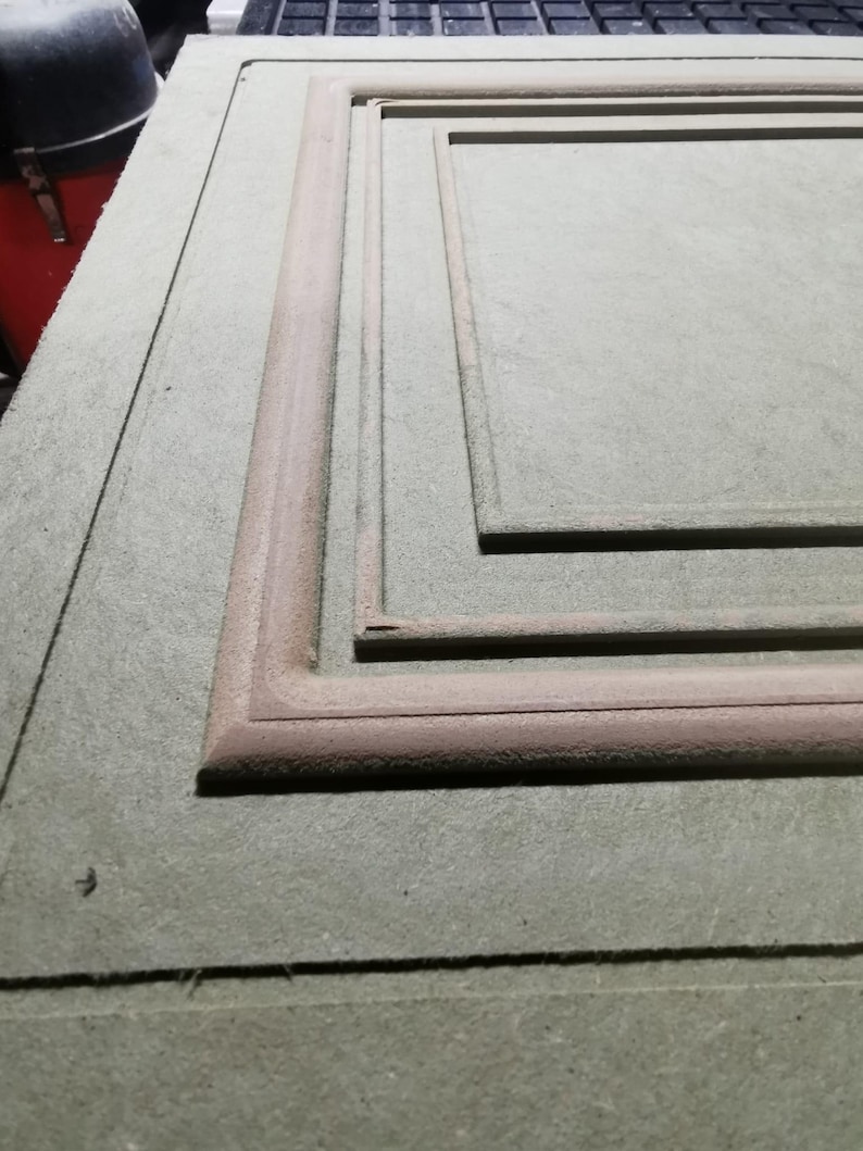 Puede incluir: Primer plano de un panel de madera gris claro con un marco rectangular empotrado. El marco es de un tono marr&oacute;n m&aacute;s oscuro y tiene un borde redondeado en relieve. El panel parece inacabado.