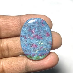 Puede incluir: Gema ovalada con base azul e inclusiones rosas y rojas. La piedra pulida tiene una sección verde en la parte inferior. Ideal para la creación de joyas, esta gema es llamativa.
