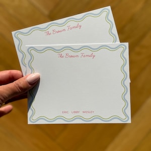 May include: Two white notecards with a wavy blue and green border. The text "The Brown Family" is in pink script at the top. The names "ERIC LIBBY WESLEY" are printed in a smaller font at the bottom.